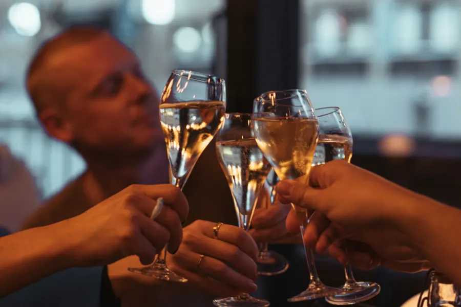 Händer som skålar med champagneglas över ett bord i kvällsljus