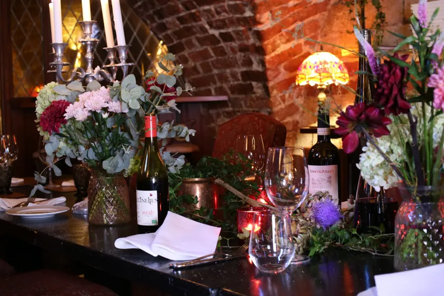 Dukat bord med kandelaber, blomsterarrangemang och vinglas under ett tegelvalv