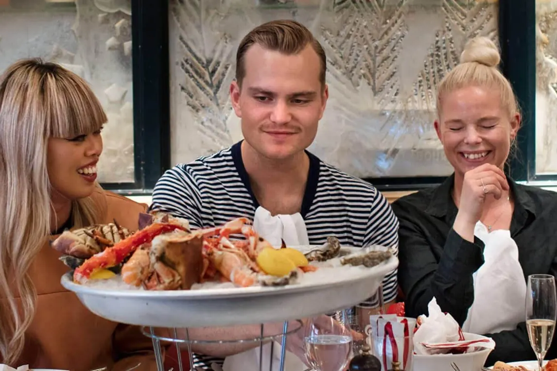 Gäster som håller upp ett skaldjursfat vid bordet