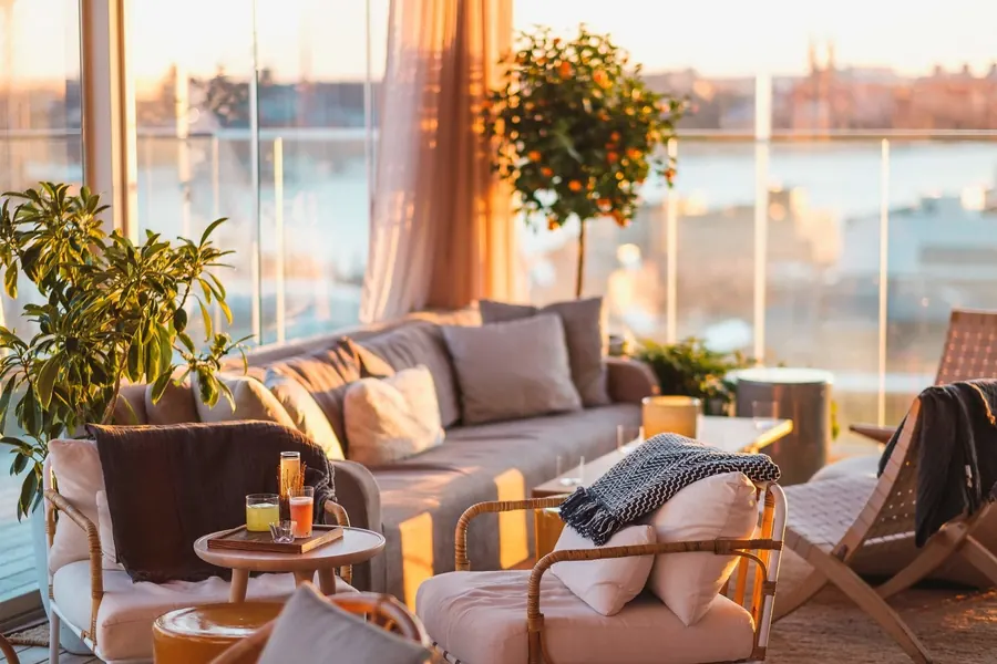 Lounge med soffor och krukväxter på en takterrass i kvällssol