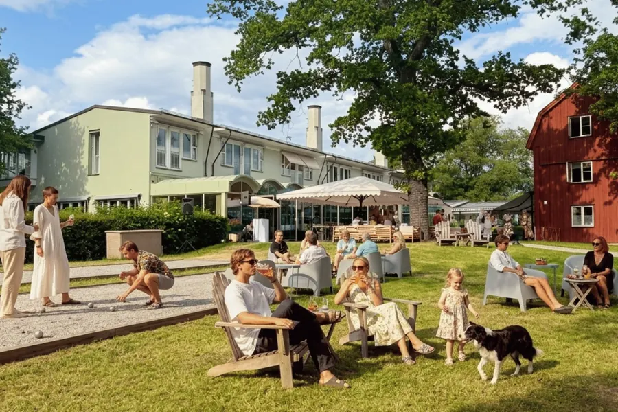 Gräsmatta med sällskap i solstolar framför en ljusgrön byggnad