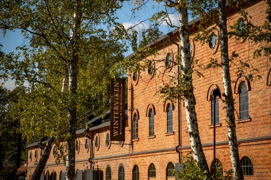 Tegelbyggnad i två våningar omgiven av björkar