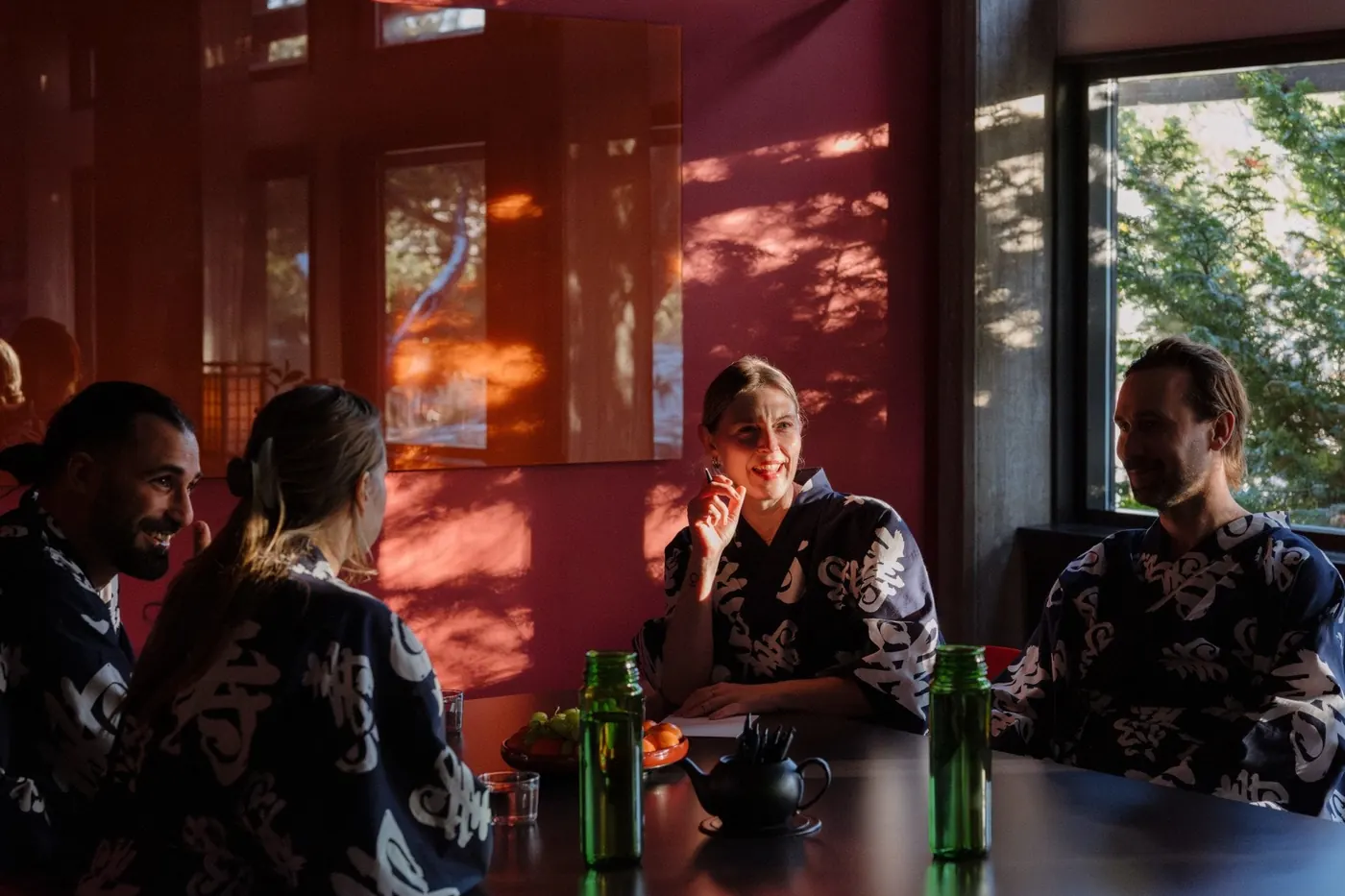 Sällskap i mönstrade morgonrockar runt ett bord i ett rött rum